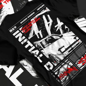 Black T-shirt laid flat with natural fabric folds, featuring Toyota AE86 racing drift jdm tuner initial d street graphic.