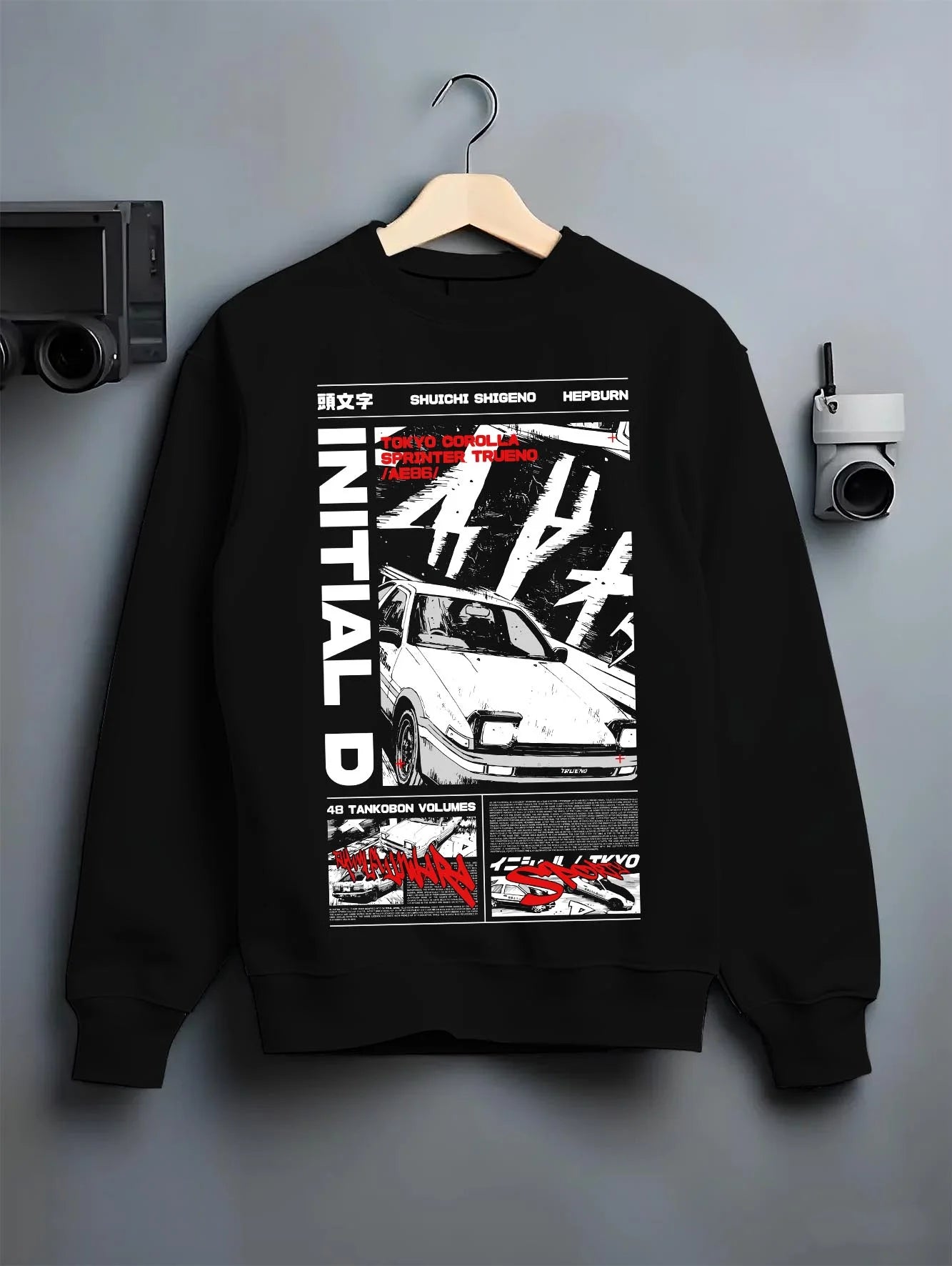 Black crewneck sweatshirt on a hanger against a grey wall, featuring Toyota AE86 racing drift jdm tuner initial d street graphic.