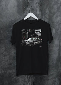 Black crewneck T-shirt on a hanger against a grey wall, featuring BMW M3 rs motorsport german racing street performance graphic.
