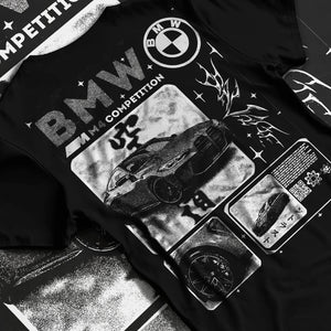 Black T-shirt laid flat with natural fabric folds, featuring BMW M4 german racing street performance motorsport automotive graphic.