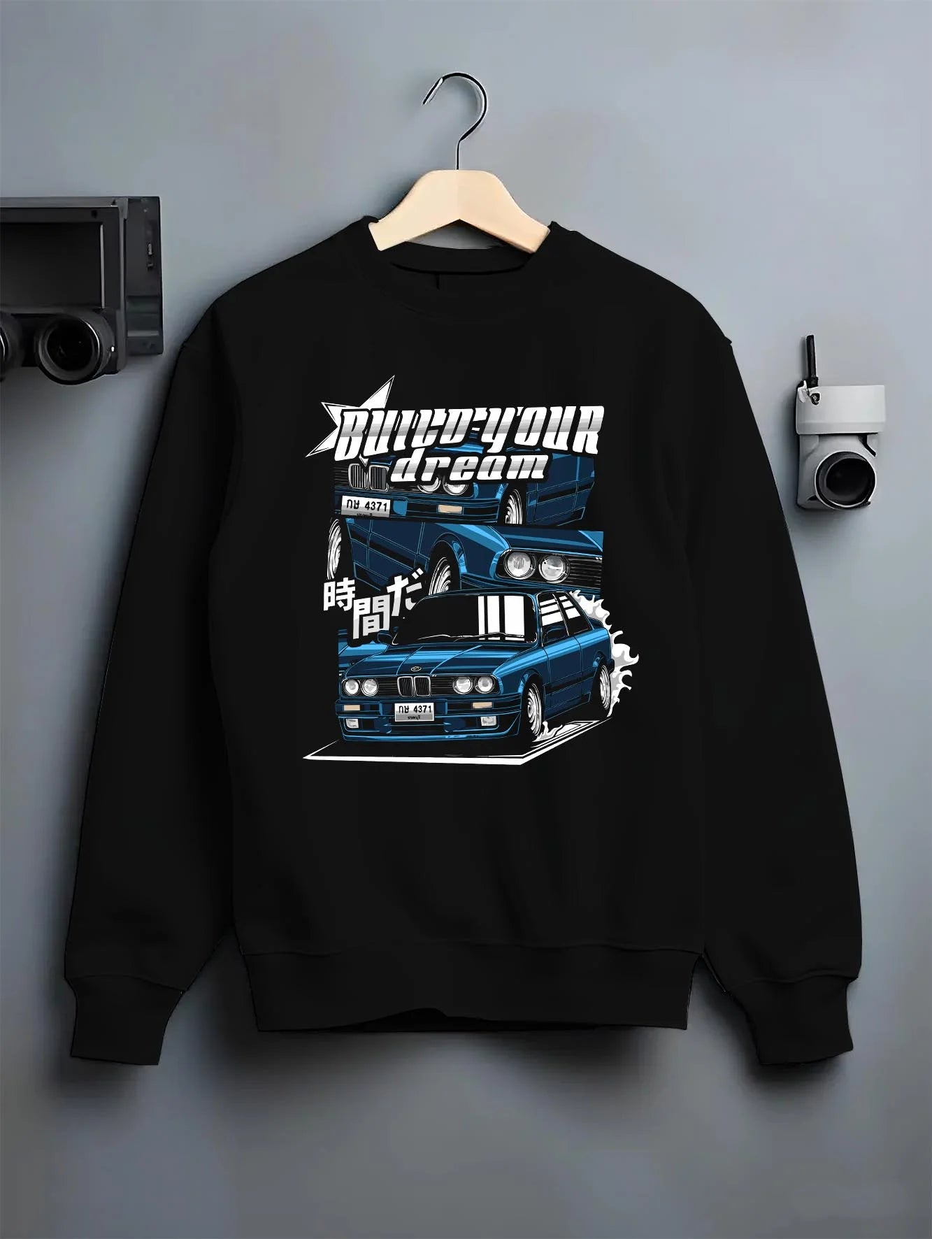 Black crewneck sweatshirt on a hanger against a grey wall, featuring BMW E30 jdm japanese retro classic enthusiast racing graphic.