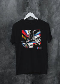 Black crewneck T-shirt on a hanger against a grey wall, featuring BMW M4 rs racing motorsport street performance automotive graphic.