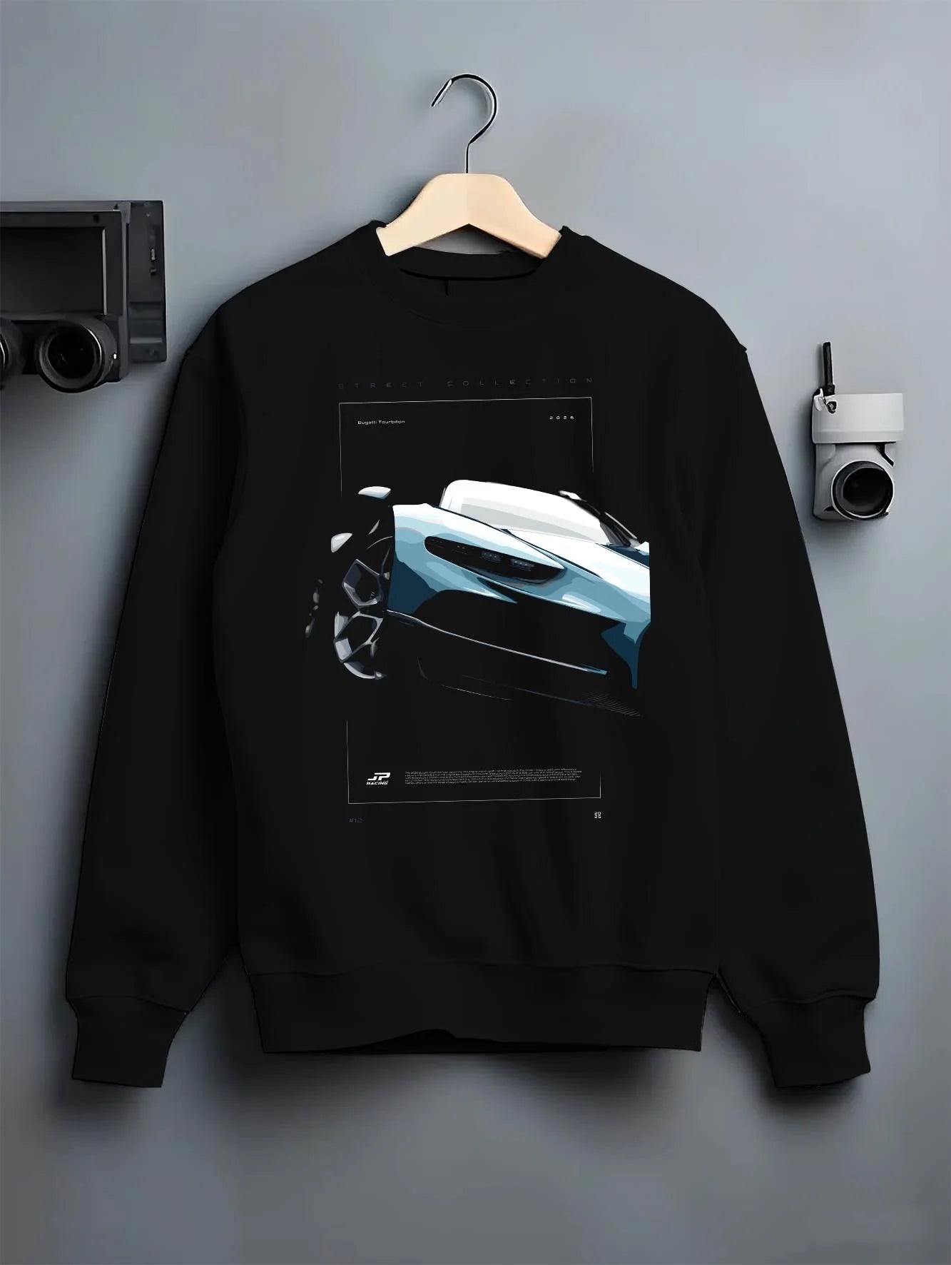 Black crewneck sweatshirt on a hanger against a grey wall, featuring Bugatti racing speed street performance motorsport graphic.