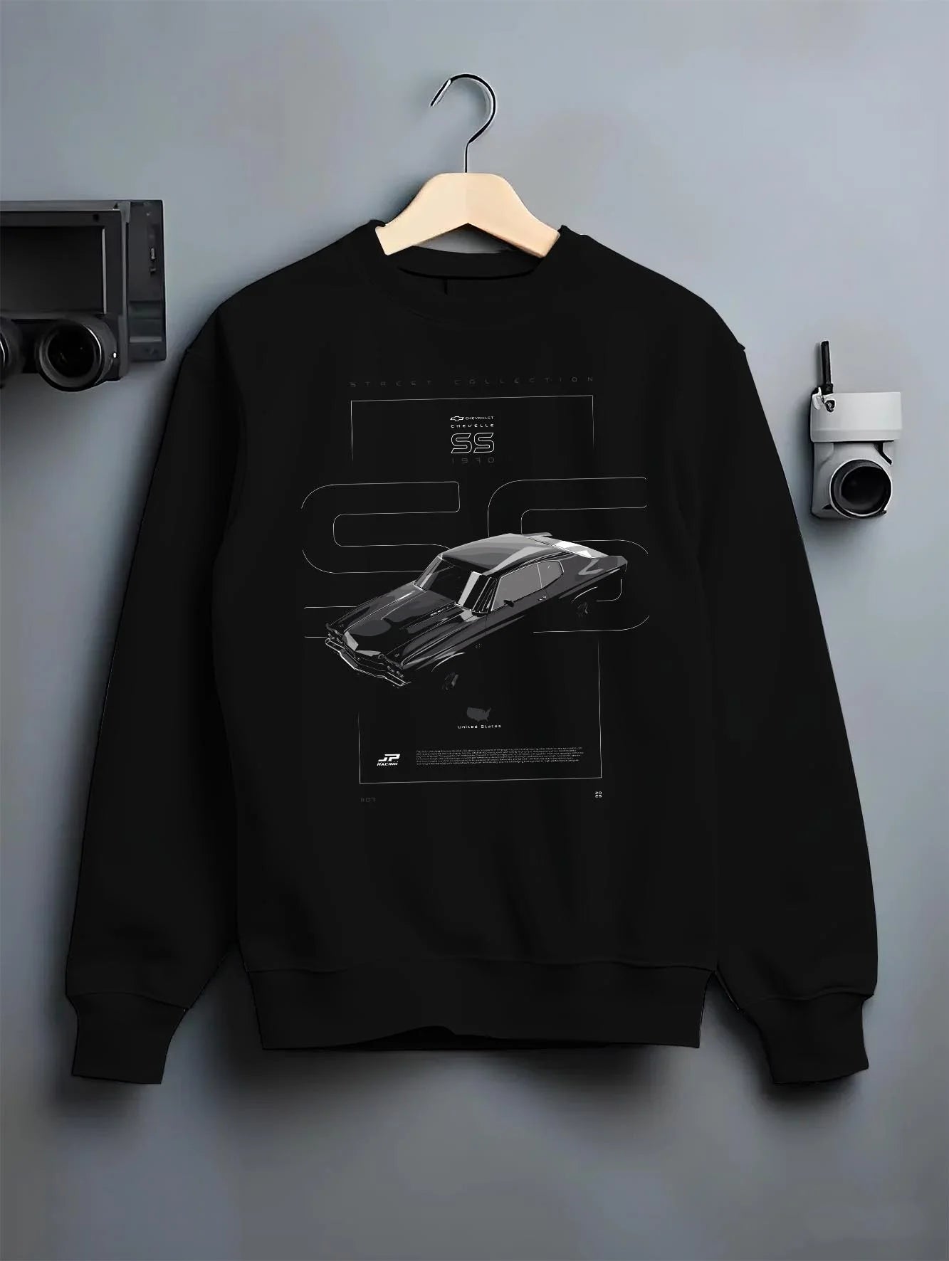 Black crewneck sweatshirt on a hanger against a grey wall, featuring Chevrolet C10 retro classic enthusiast racing street graphic.