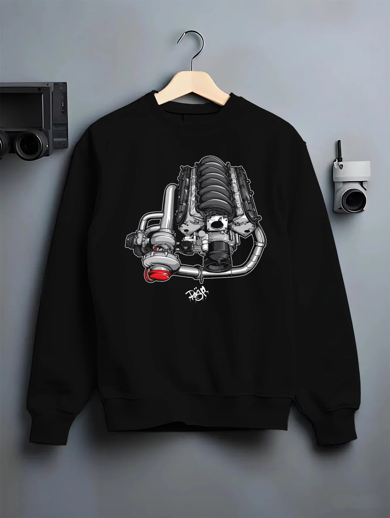 Black crewneck sweatshirt on a hanger against a grey wall, featuring supercharged v8 muscle street retro power enthusiast graphic.
