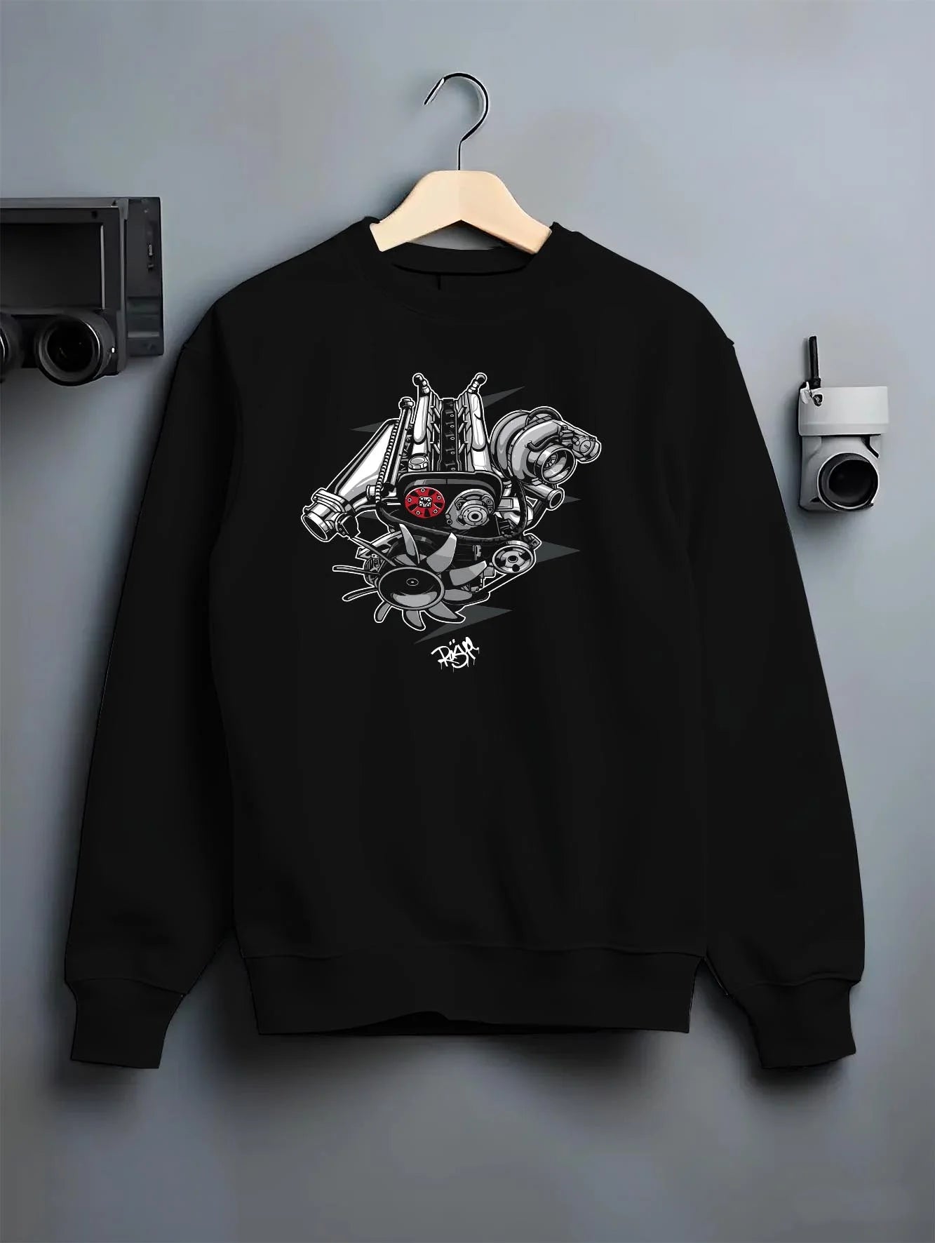 Black crewneck sweatshirt on a hanger against a grey wall, featuring muscle retro vintage racing street performance graphic.