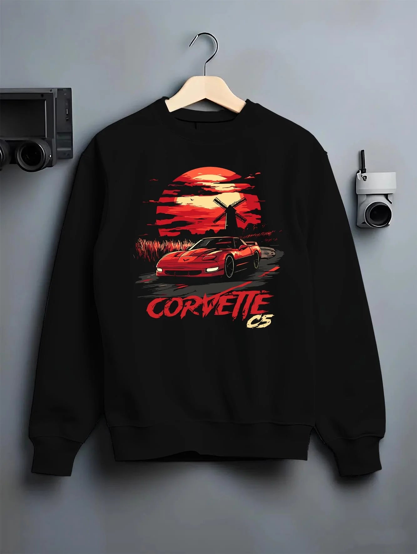 Black crewneck sweatshirt on a hanger against a grey wall, featuring Chevrolet Camaro racing drag american muscle street graphic.