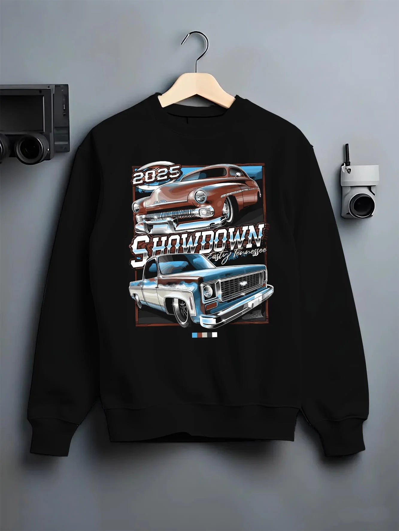 Black crewneck sweatshirt on a hanger against a grey wall, featuring racing american muscle retro vintage classic show graphic.