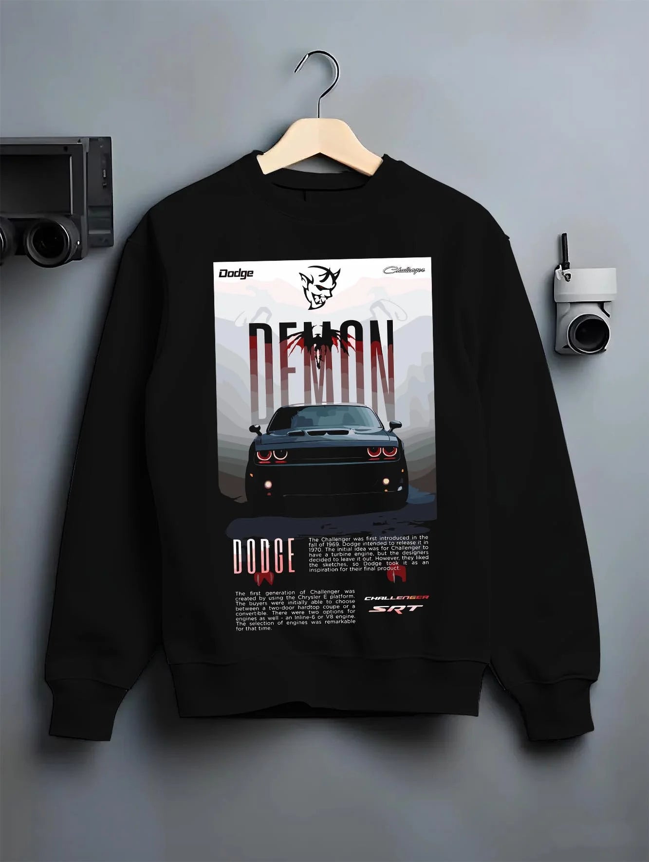 Black crewneck sweatshirt on a hanger against a grey wall, featuring Dodge Challenger racing muscle street retro enthusiast graphic.