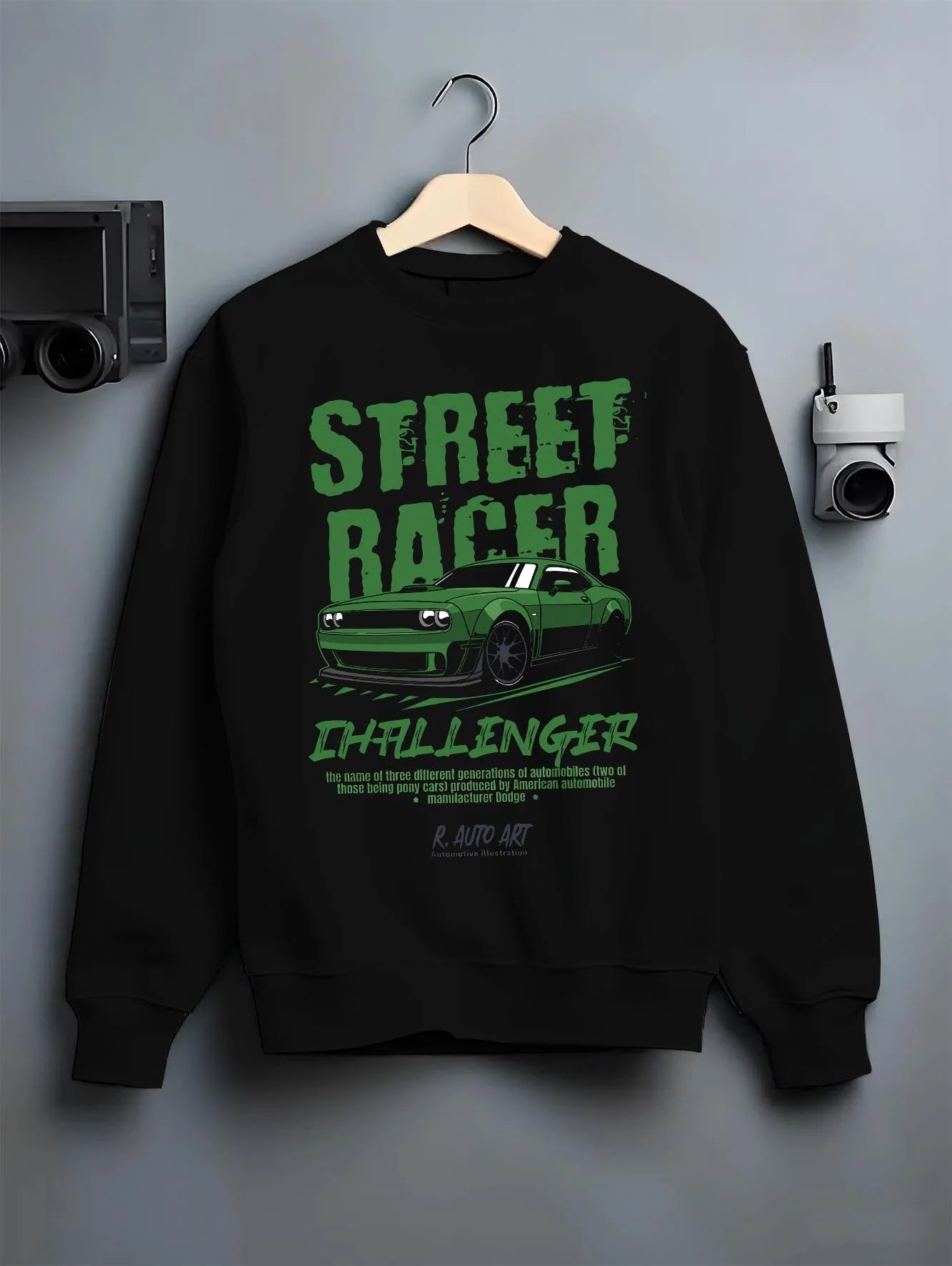 Black crewneck sweatshirt on a hanger against a grey wall, featuring Dodge Challenger racing race muscle street retro graphic.