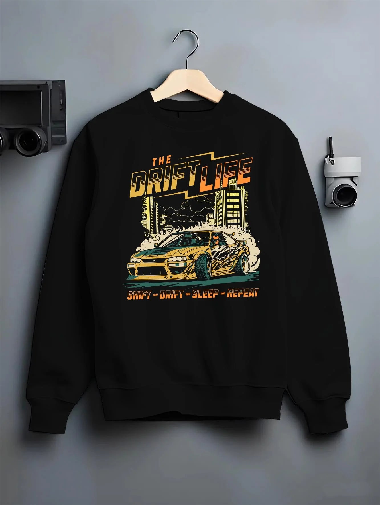 Black crewneck sweatshirt on a hanger against a grey wall, featuring racing drift jdm street retro vintage performance graphic.