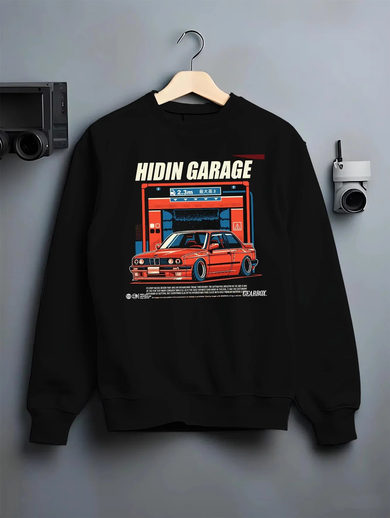 Black crewneck sweatshirt on a hanger against a grey wall, featuring BMW E30 racing drift jdm euro street retro classic graphic.