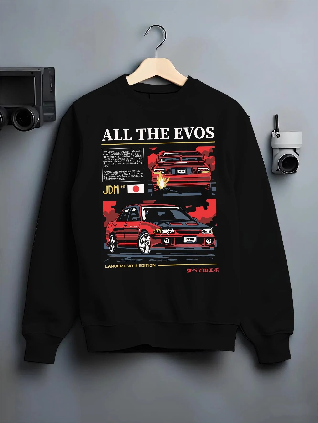 Black crewneck sweatshirt on a hanger against a grey wall, featuring Mitsubishi Lancer Evo III evo lancer turbo jdm legend graphic.