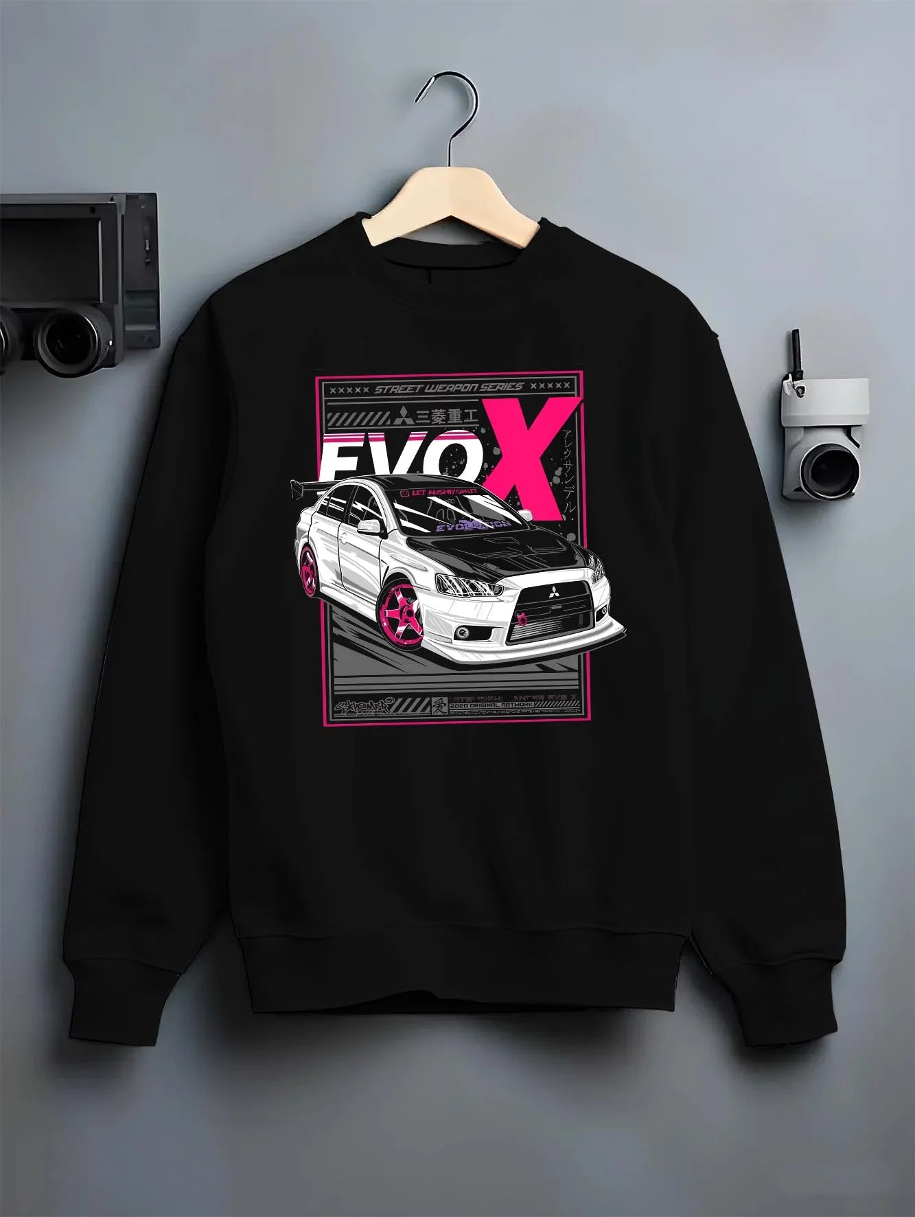 Black crewneck sweatshirt on a hanger against a grey wall, featuring Mitsubishi Lancer Evo X evo lancer jdm street racing graphic.