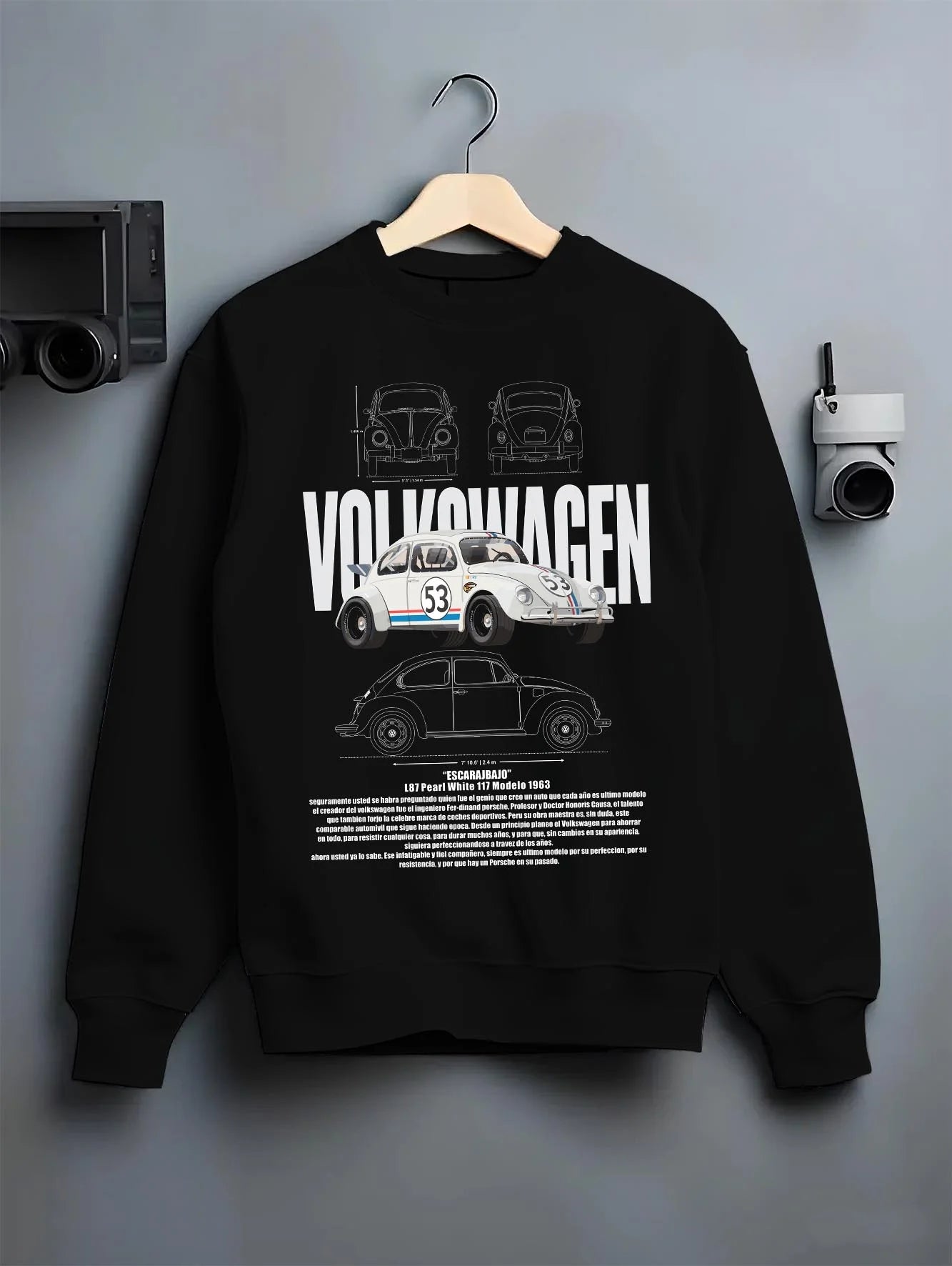 Black crewneck sweatshirt on a hanger against a grey wall, featuring Volkswagen Beetle racing classic legend street graphic.