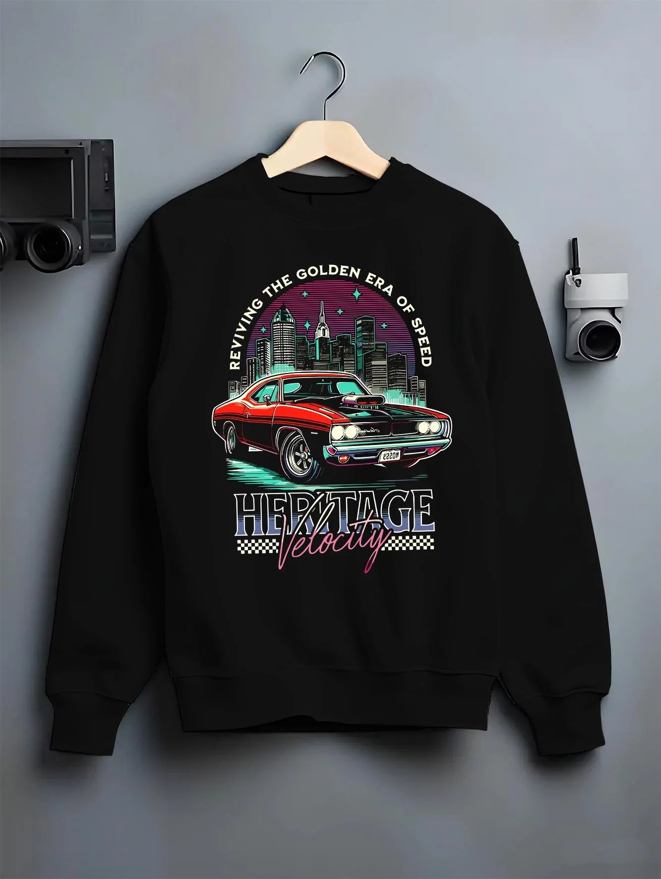 Black crewneck sweatshirt on a hanger against a grey wall, featuring Dodge Charger muscle retro racing street performance graphic.