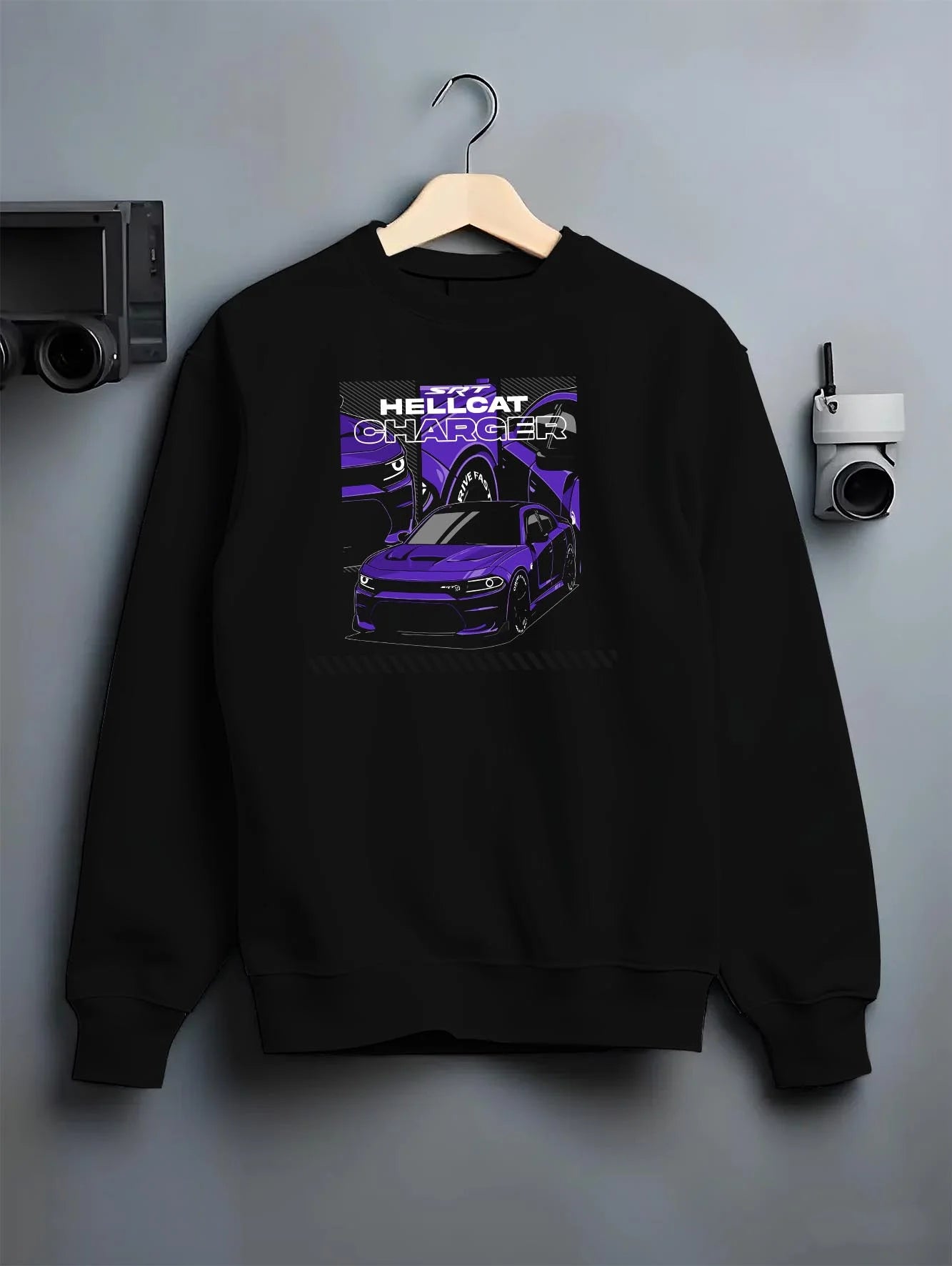 Black crewneck sweatshirt on a hanger against a grey wall, featuring Dodge Charger Hellcat hellcat srt charger racing graphic.