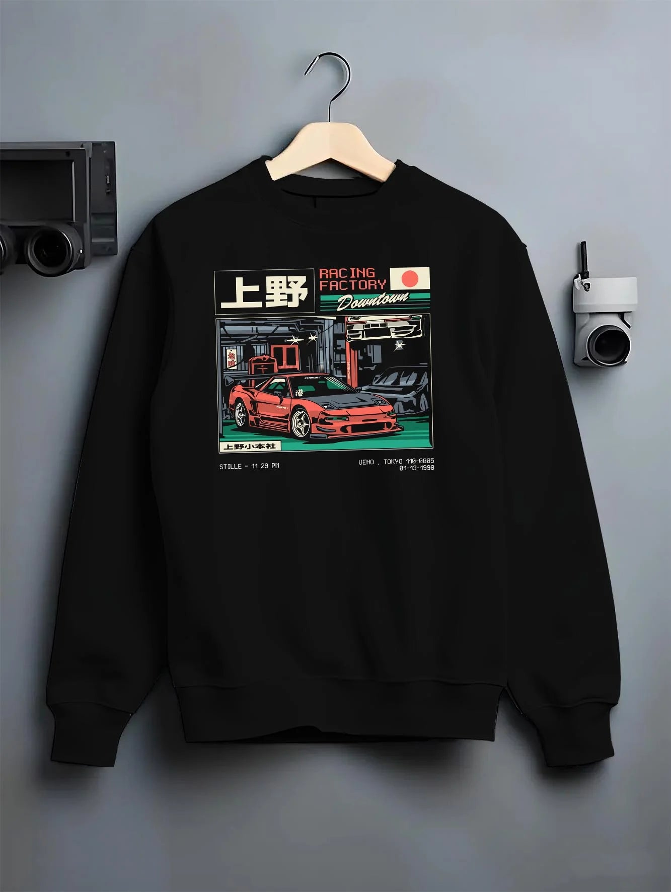 Black crewneck sweatshirt on a hanger against a grey wall, featuring Honda rs racing motorsport street retro classic speed graphic.