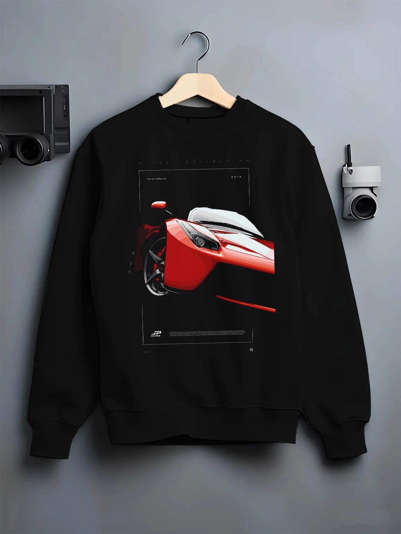 Black crewneck sweatshirt on a hanger against a grey wall, featuring Ferrari rs racing street performance motorsport graphic.