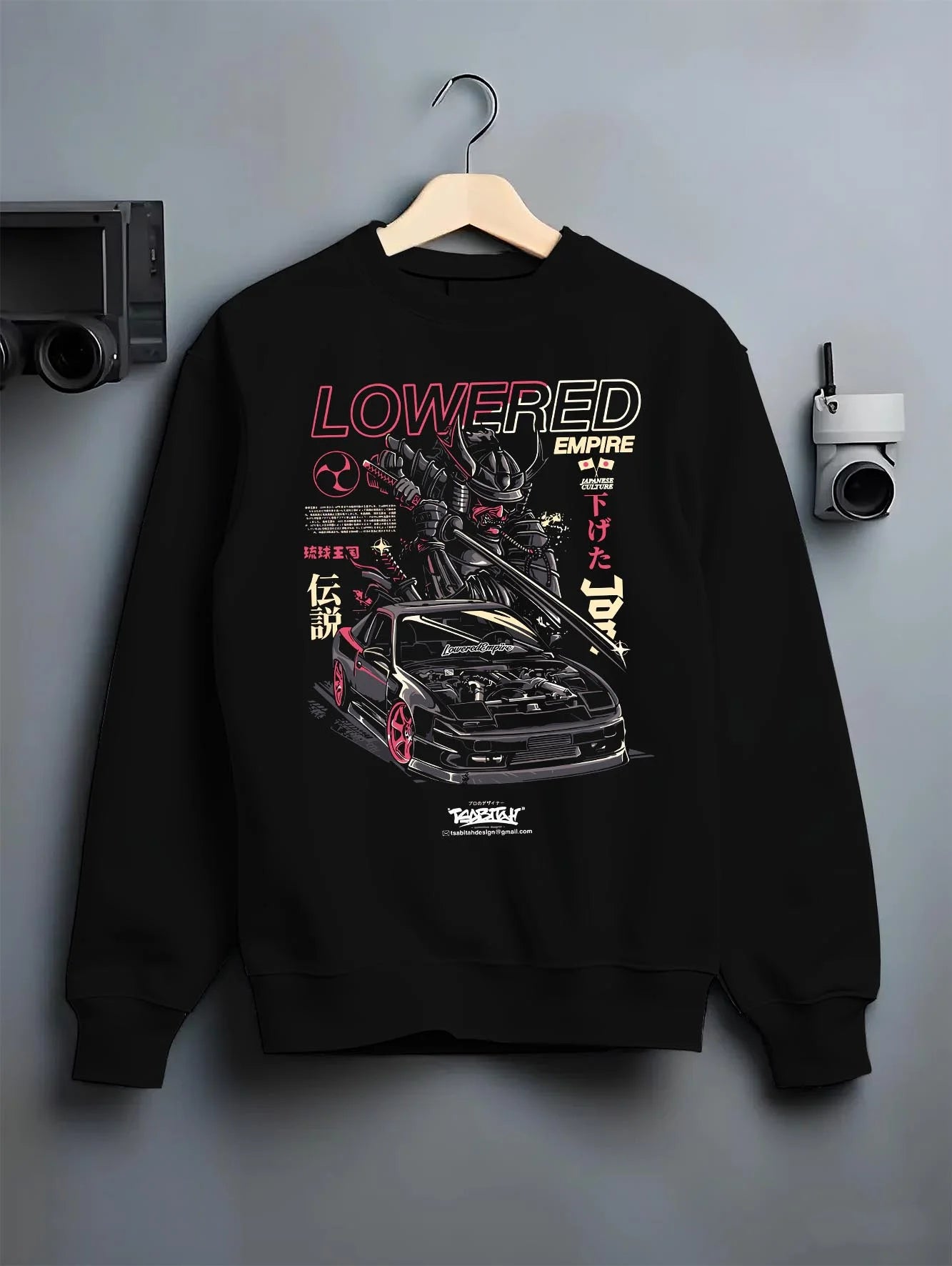Black crewneck sweatshirt on a hanger against a grey wall, featuring drift drifting japanese tuner lowered street racing graphic.