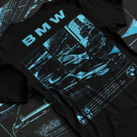 Black T-shirt laid flat with natural fabric folds, featuring BMW M5 rs turbo racing motorsport euro german street graphic.