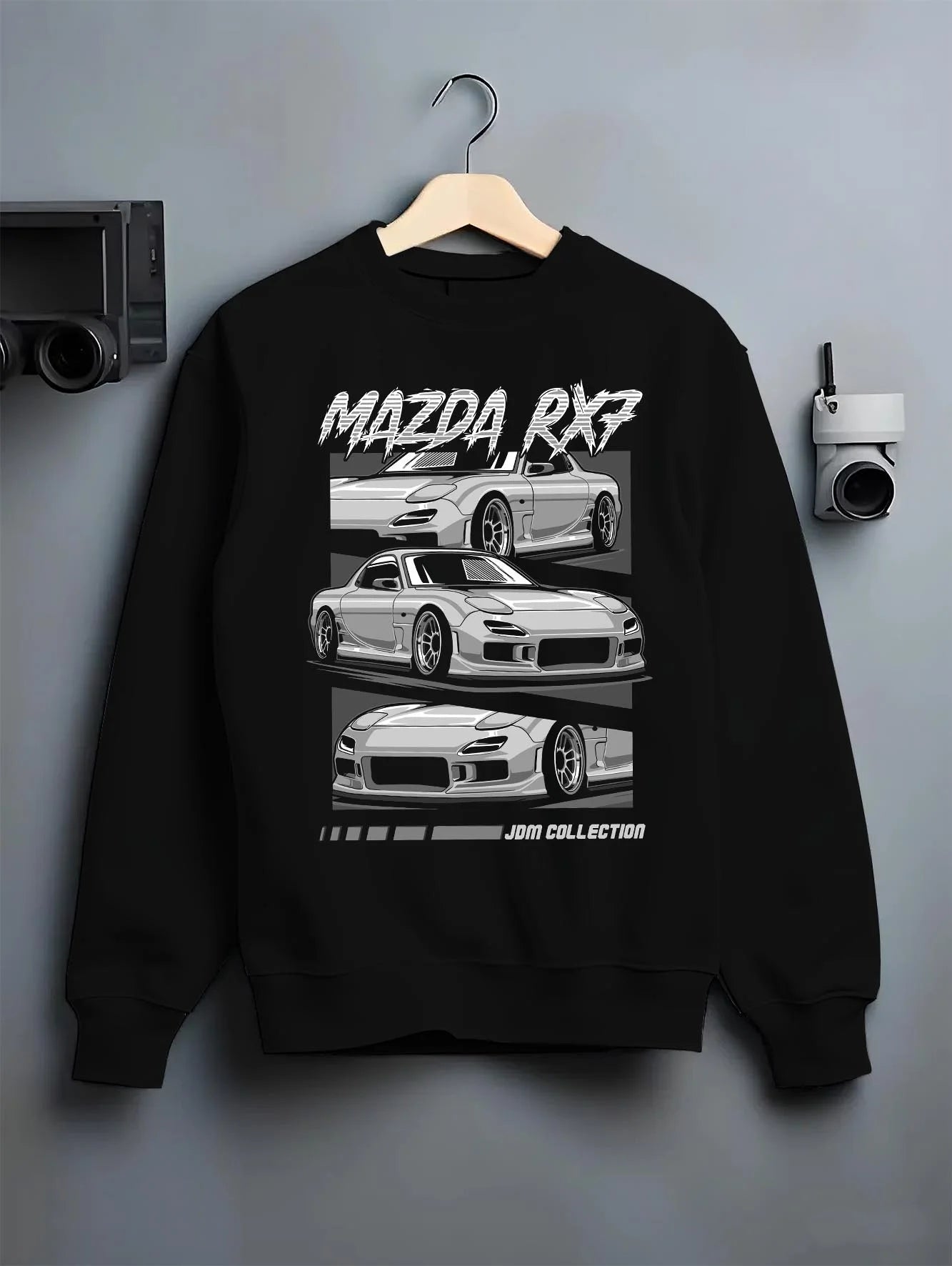 Black crewneck sweatshirt on a hanger against a grey wall, featuring Mazda RX--7 rx 7 racing drift jdm japanese street graphic.