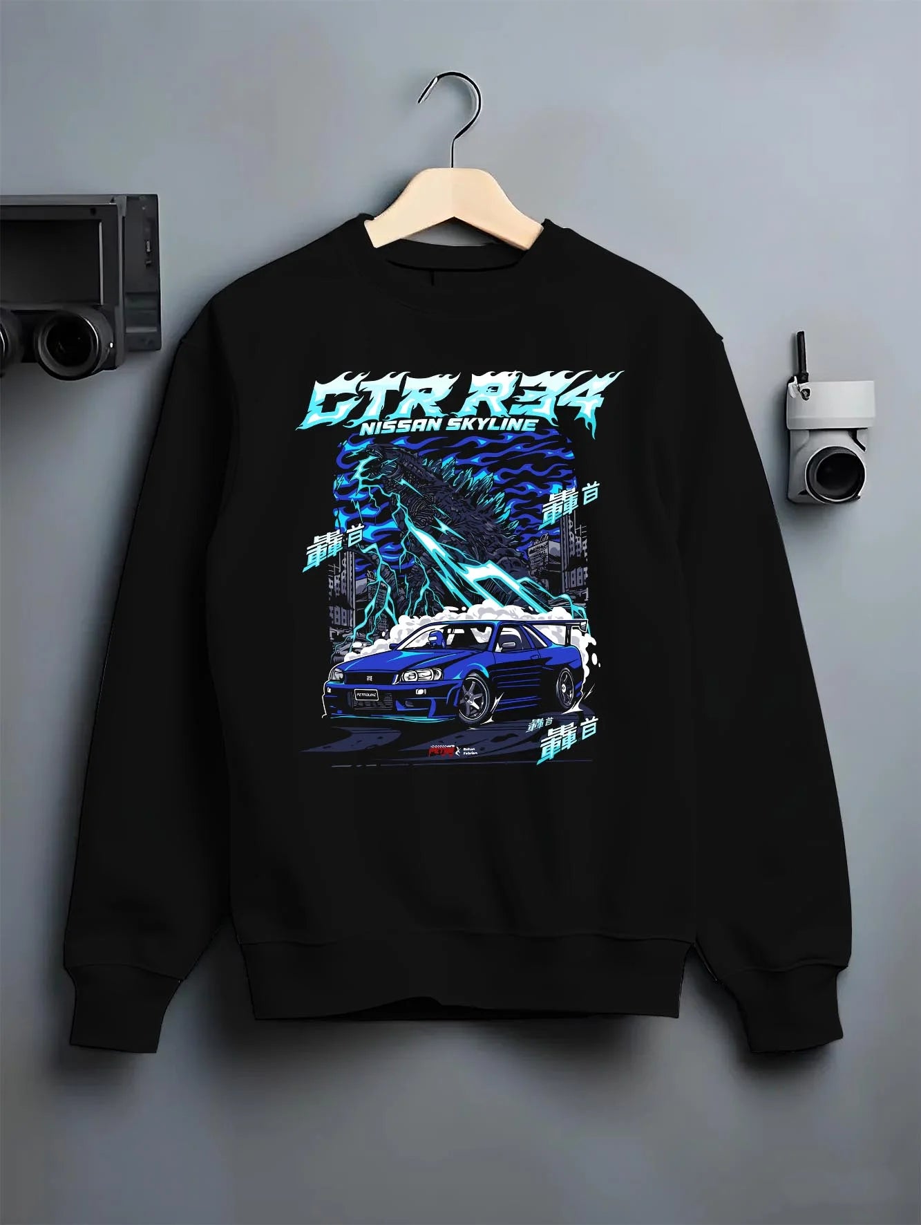 Black crewneck sweatshirt on a hanger against a grey wall, featuring Nissan Skyline R34 gtr r34 skyline racing drift jdm graphic.