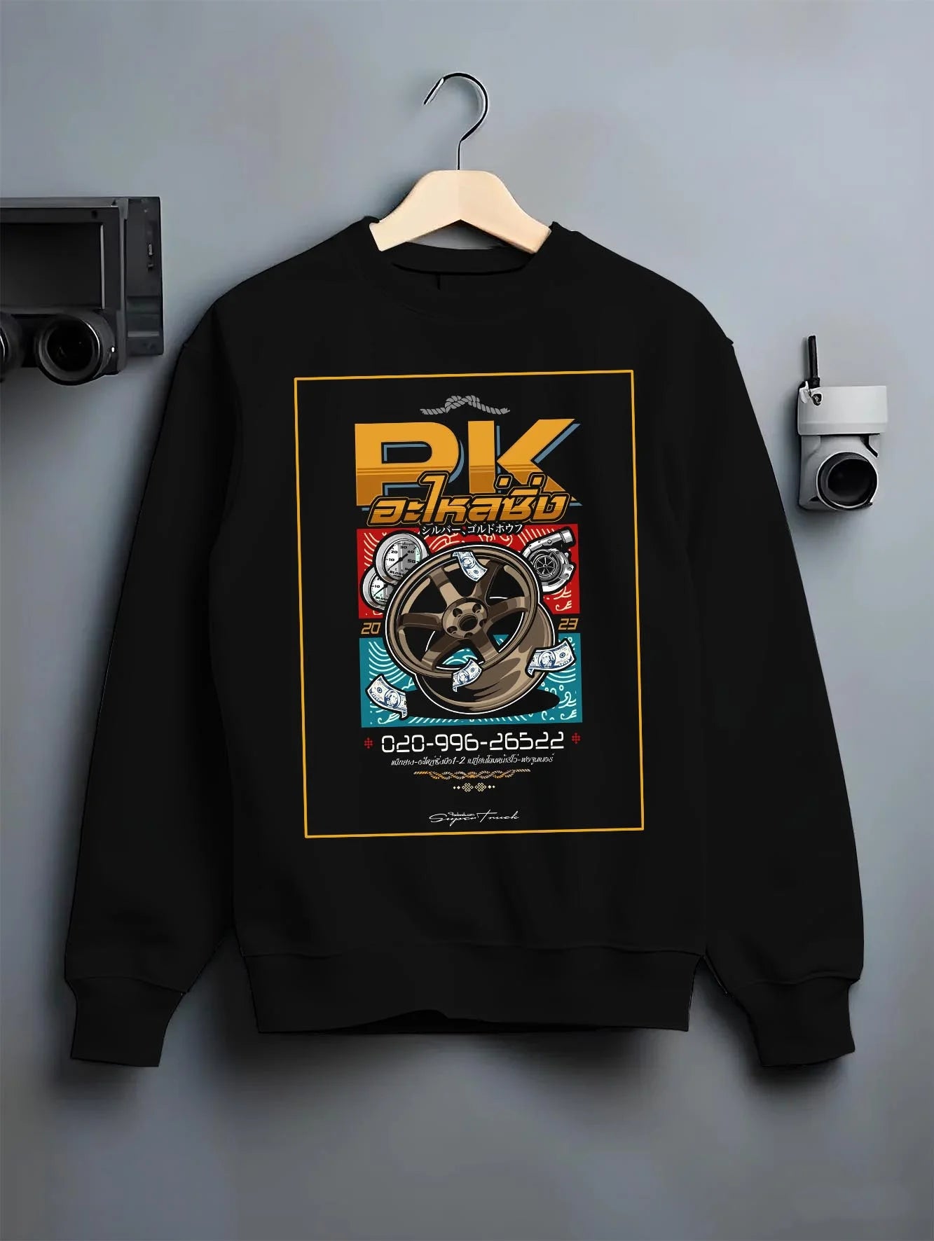 Black crewneck sweatshirt on a hanger against a grey wall, featuring street racing performance motorsport automotive pkauto.
