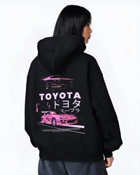 Black hoodie worn by a female model, back view, featuring Toyota Supra racing drift jdm japanese tuner street retro graphic.