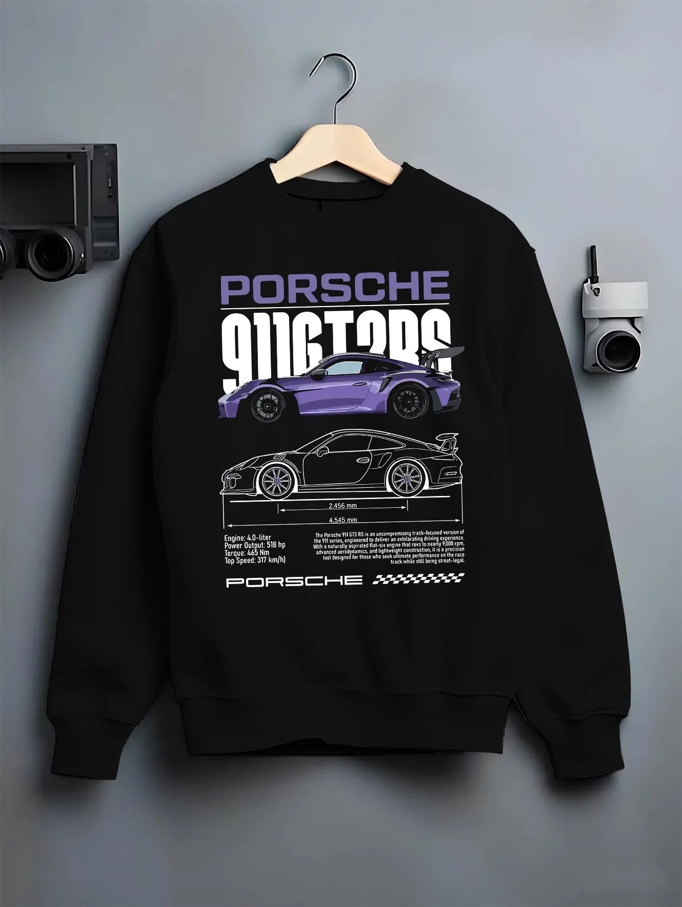 Black crewneck sweatshirt on a hanger against a grey wall, featuring Porsche Taycan rs turbo turbocharged racing german graphic.