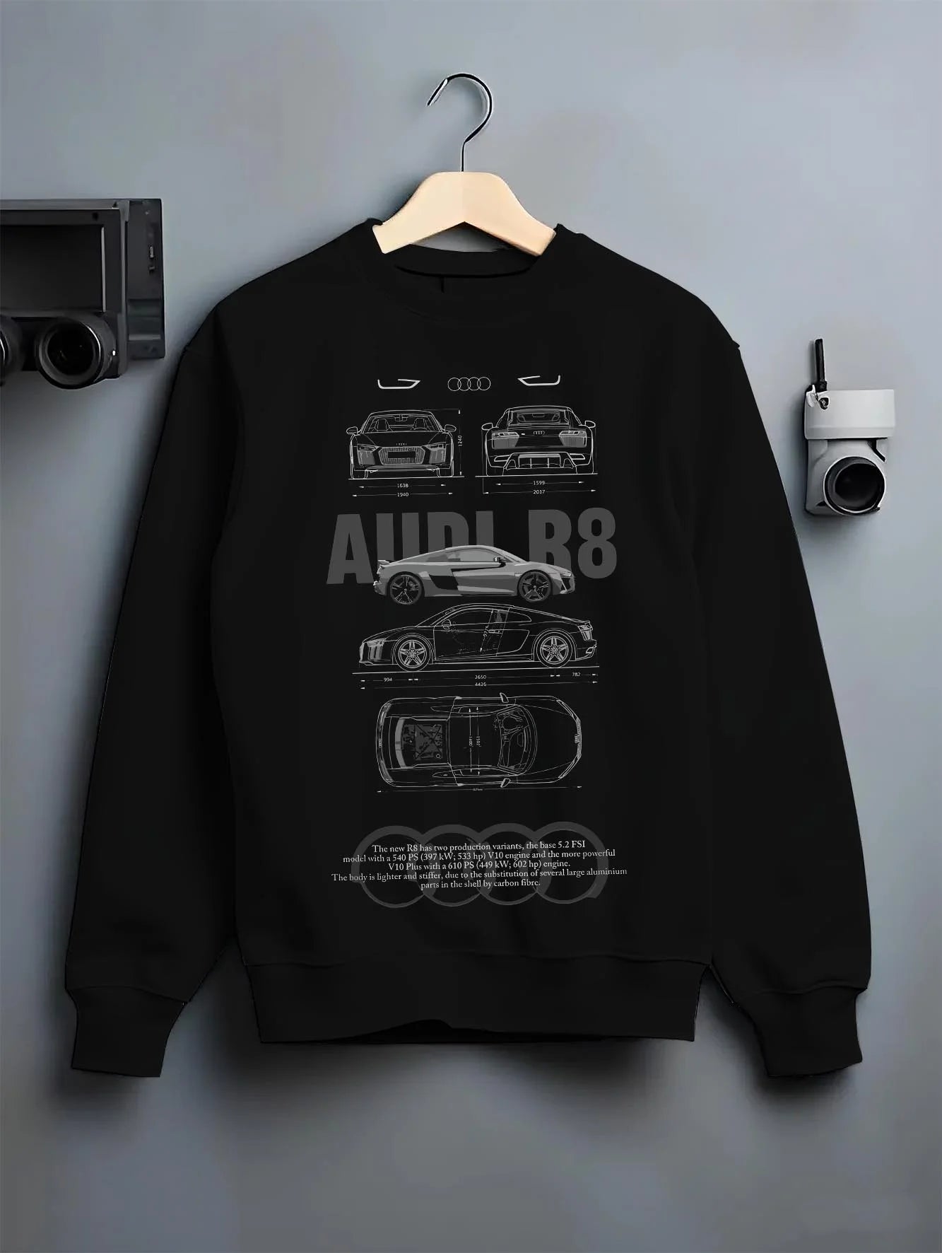 Black crewneck sweatshirt on a hanger against a grey wall, featuring Audi R8 v10 racing german street performance graphic.