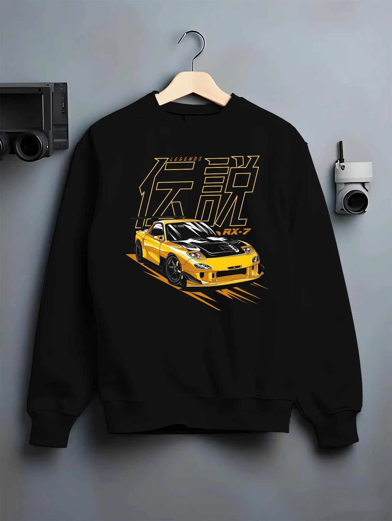 Black crewneck sweatshirt on a hanger against a grey wall, featuring Mazda RX-7 rx7 racing drift japanese tuner stance graphic.