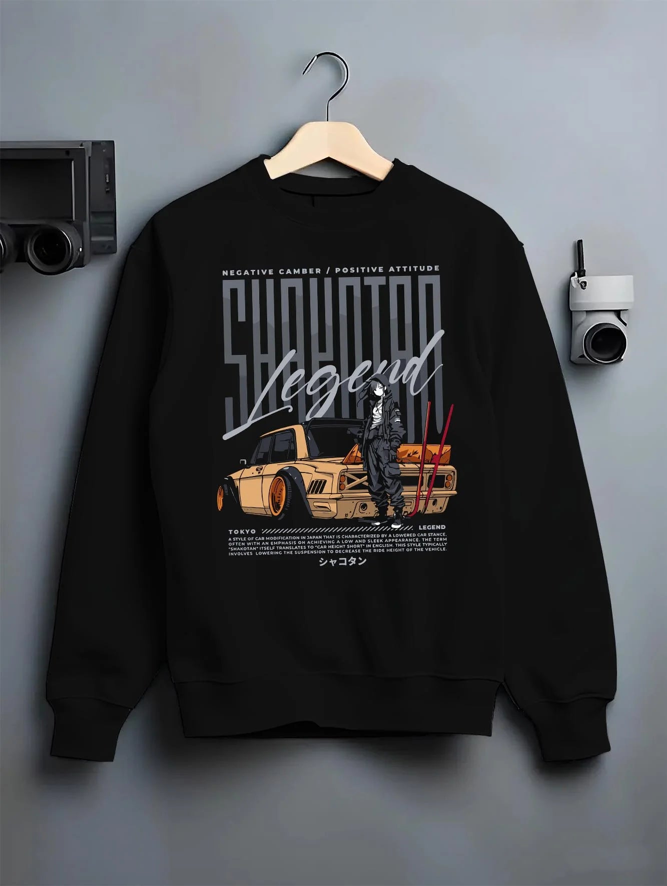 Black crewneck sweatshirt on a hanger against a grey wall, featuring Toyota jdm stance legend racing street performance graphic.