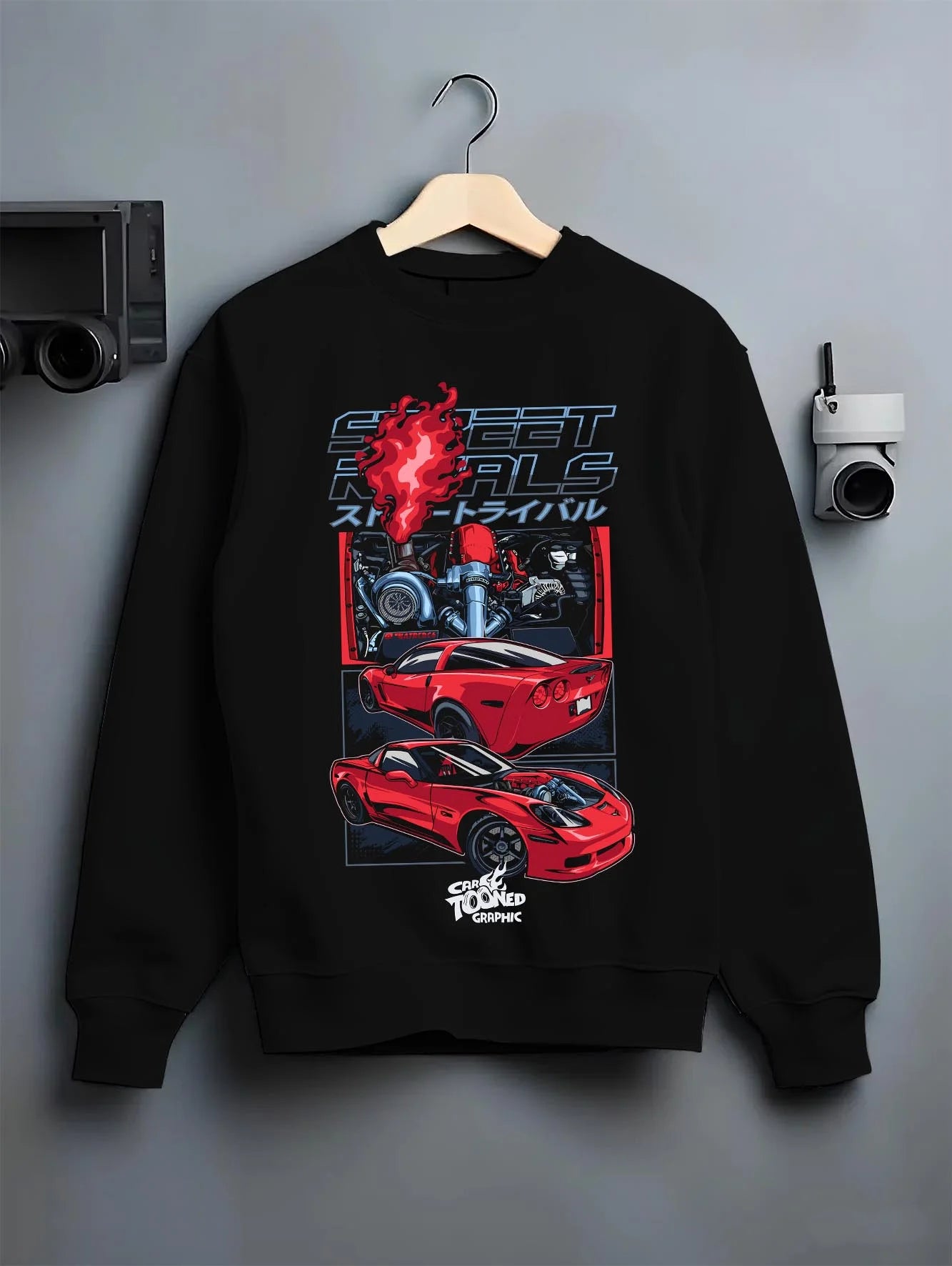 Black crewneck sweatshirt on a hanger against a grey wall, featuring Chevrolet Corvette turbo ls racing street performance graphic.