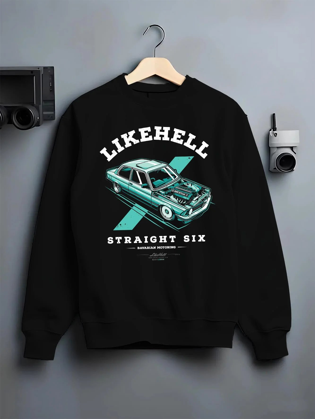 Black crewneck sweatshirt on a hanger against a grey wall, featuring BMW racing drift tuner street enthusiast performance graphic.