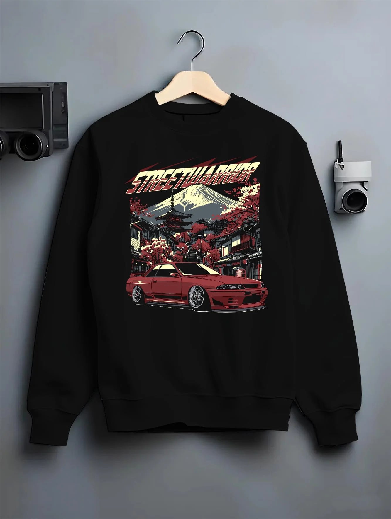 Black crewneck sweatshirt on a hanger against a grey wall, featuring SKYLINE r32 drift jdm street retro racing performance graphic.