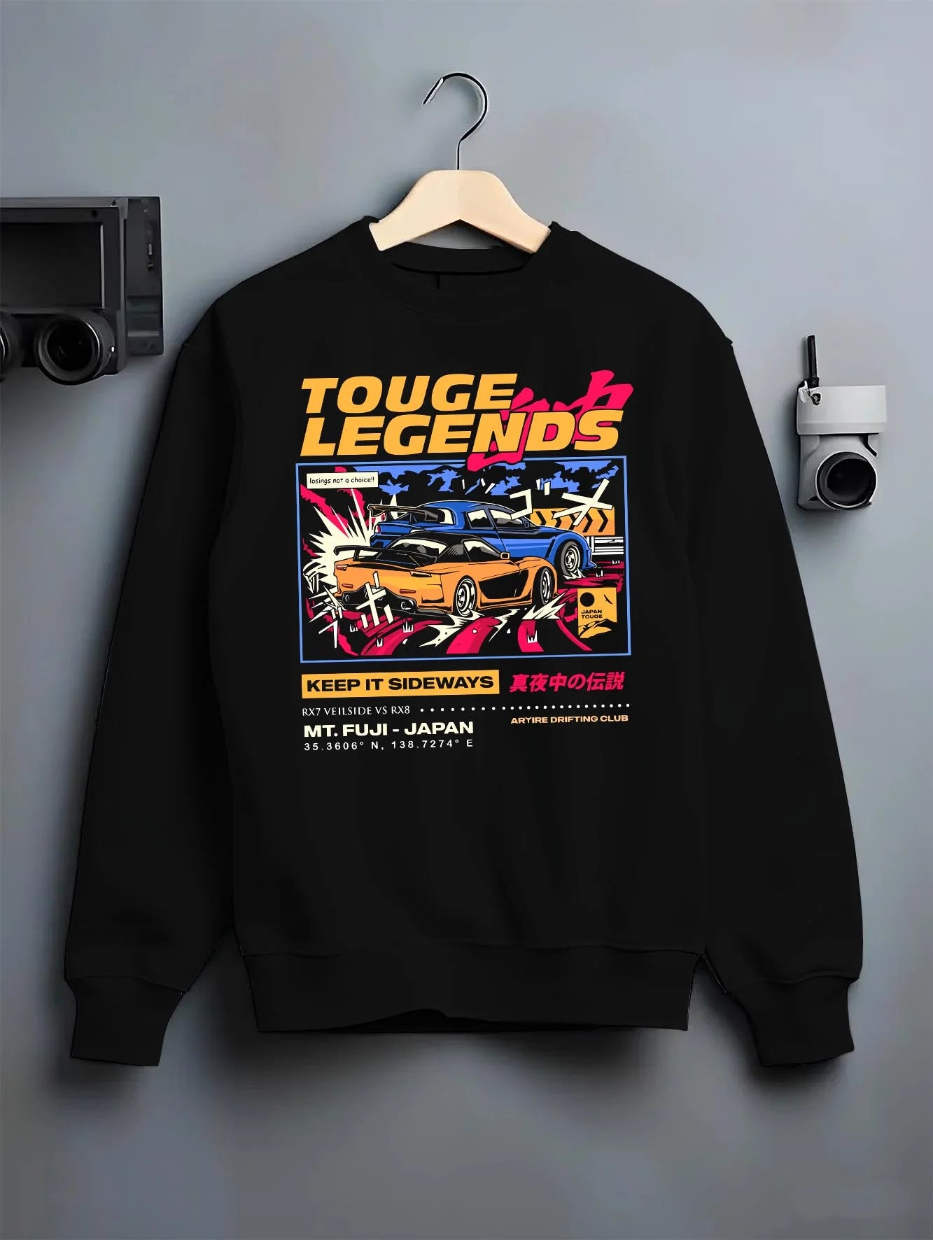 Black crewneck sweatshirt on a hanger against a grey wall, featuring RX7 ls racing drift jdm street legend performance graphic.