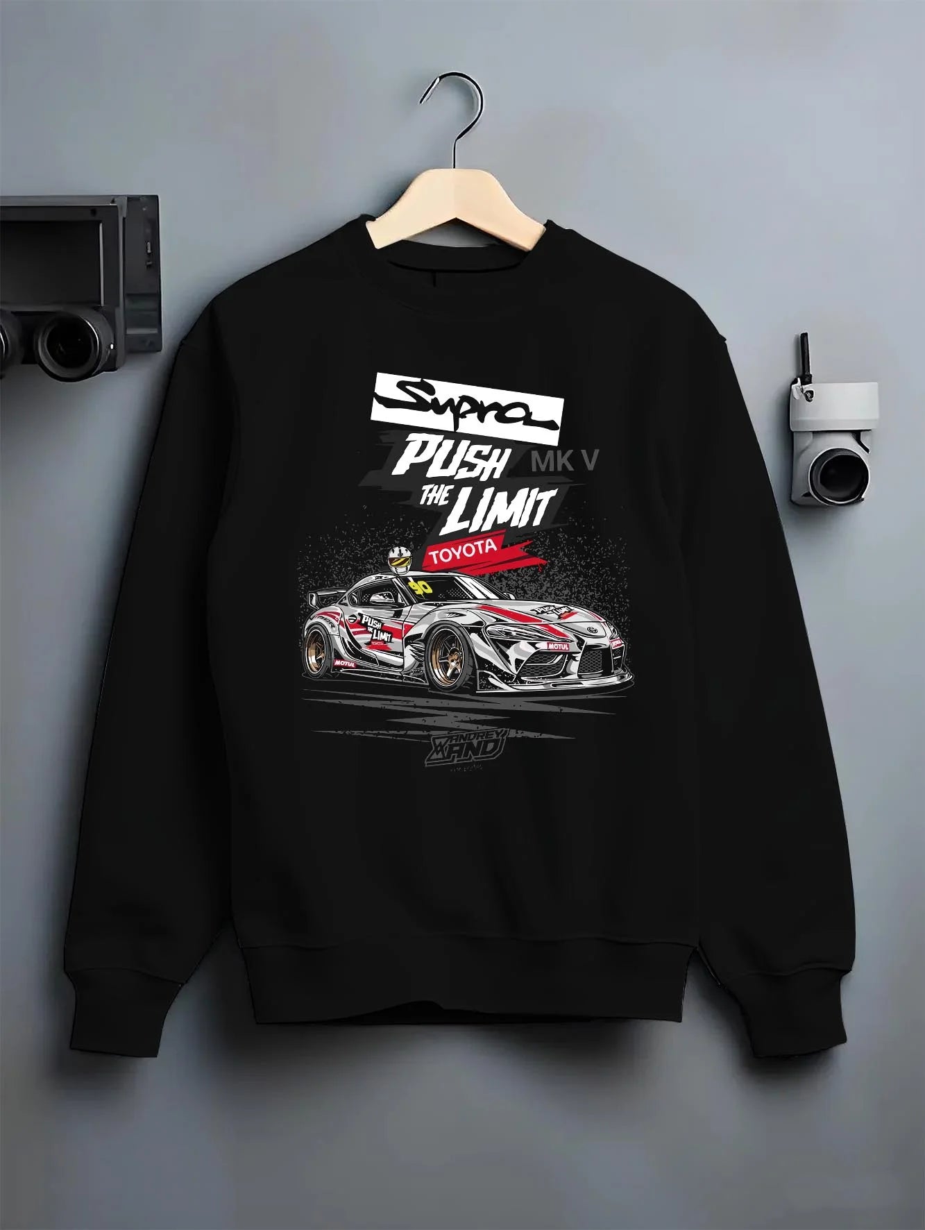 Black crewneck sweatshirt on a hanger against a grey wall, featuring Toyota Supra MK4 supra turbo turbocharged racing drift toy16.