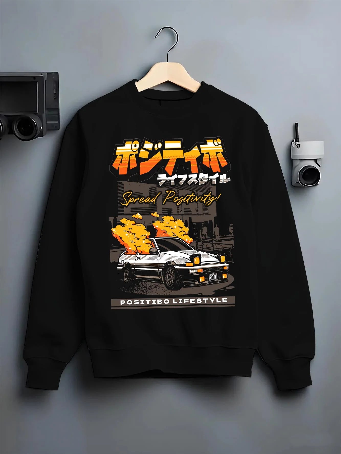 Black crewneck sweatshirt on a hanger against a grey wall, featuring Toyota AE86 drift jdm racing street performance graphic.