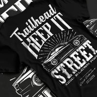 Black T-shirt laid flat with natural fabric folds, featuring rs racing race street enthusiast performance motorsport graphic.