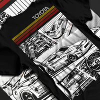 Black T-shirt laid flat with natural fabric folds, featuring Toyota Supra rs racing jdm tuner street vintage enthusiast graphic.