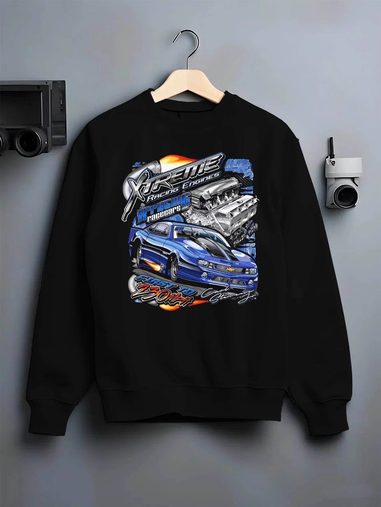 Black crewneck sweatshirt on a hanger against a grey wall, featuring turbo racing drag jdm muscle street performance graphic.