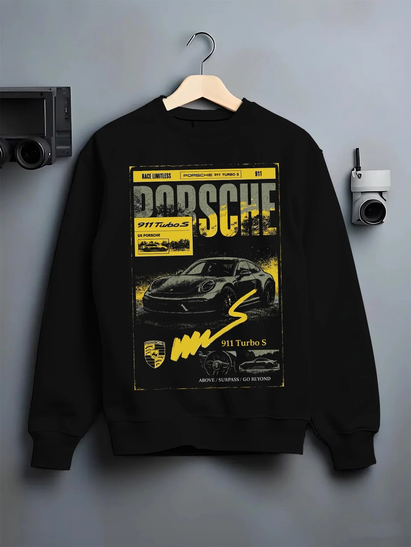 Black crewneck sweatshirt on a hanger against a grey wall, featuring Porsche 911 Turbo S rs 911 turbo racing german street graphic.