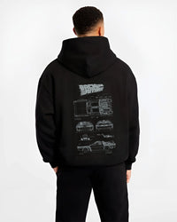 Black hoodie worn by a male model, back view, featuring DeLorean DMC-12 street retro racing performance motorsport graphic.