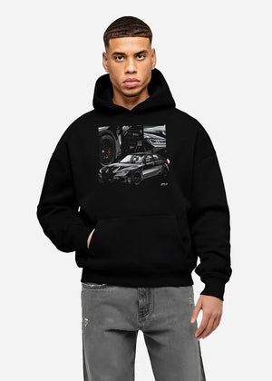 Black hoodie worn by a male model, front view, featuring BMW M3 rs motorsport german racing street performance graphic.