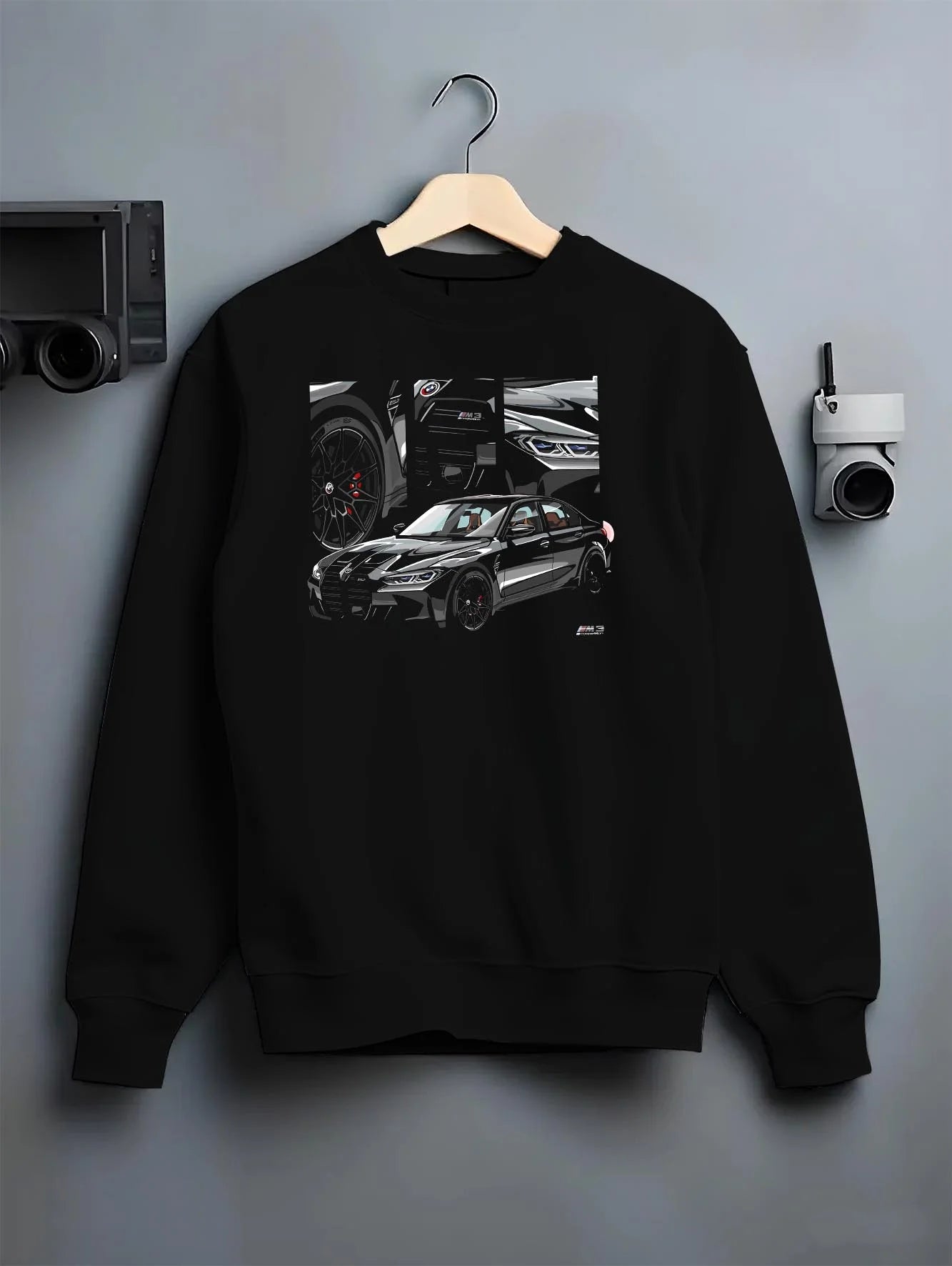 Black crewneck sweatshirt on a hanger against a grey wall, featuring BMW M3 rs motorsport german racing street performance graphic.