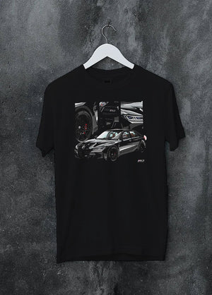 Black crewneck T-shirt on a hanger against a grey wall, featuring BMW M3 rs motorsport german racing street performance graphic.