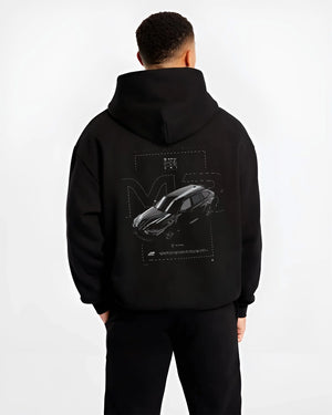 Black hoodie worn by a male model, back view, featuring BMW M3 street racing performance motorsport automotive enthusiast graphic.