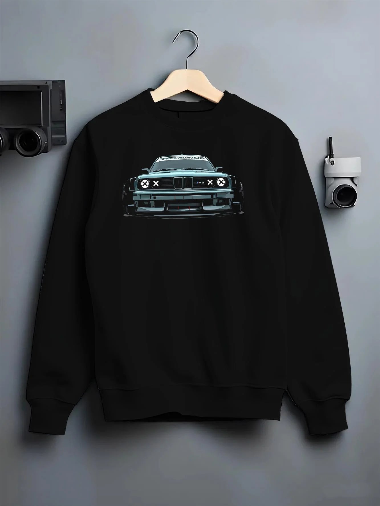 Black crewneck sweatshirt on a hanger against a grey wall, featuring BMW M3 rs drift classic racing street performance graphic.