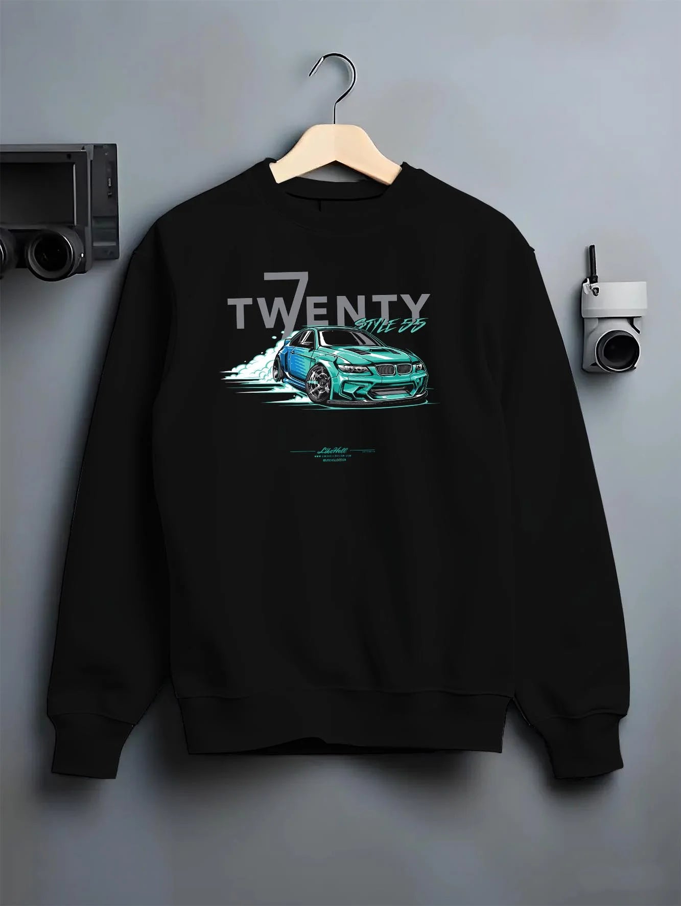 Black crewneck sweatshirt on a hanger against a grey wall, featuring BMW turbo drift racing street performance motorsport graphic.